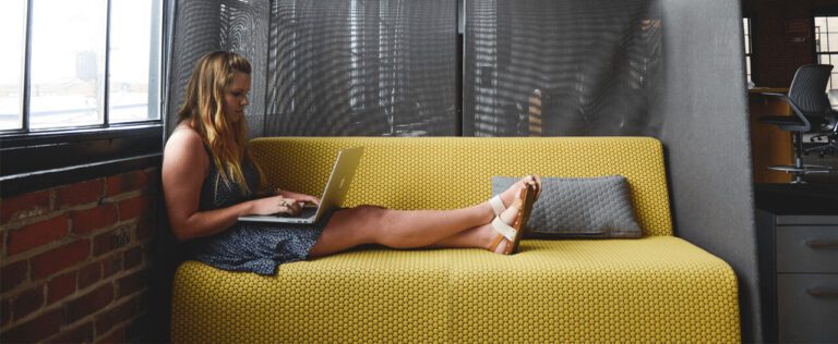 A Girl Sitting On A Couch Using Laptop