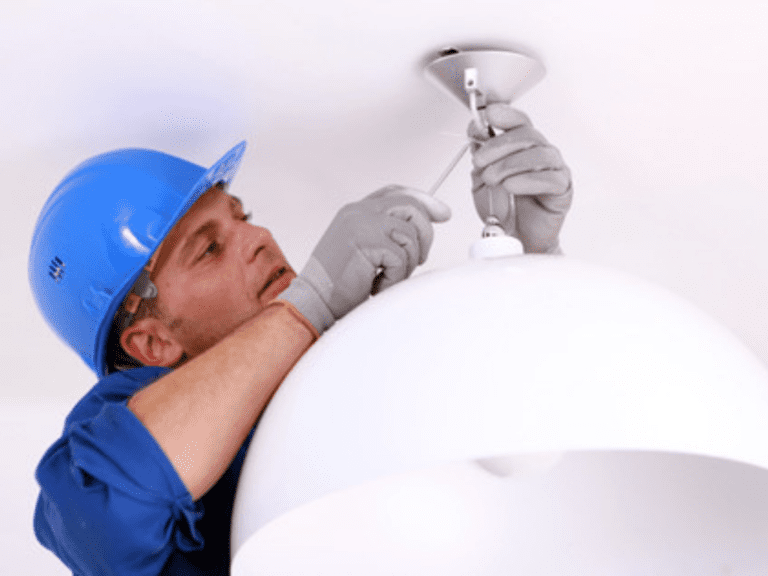 A Man Fixing Light In A Room With A White Background