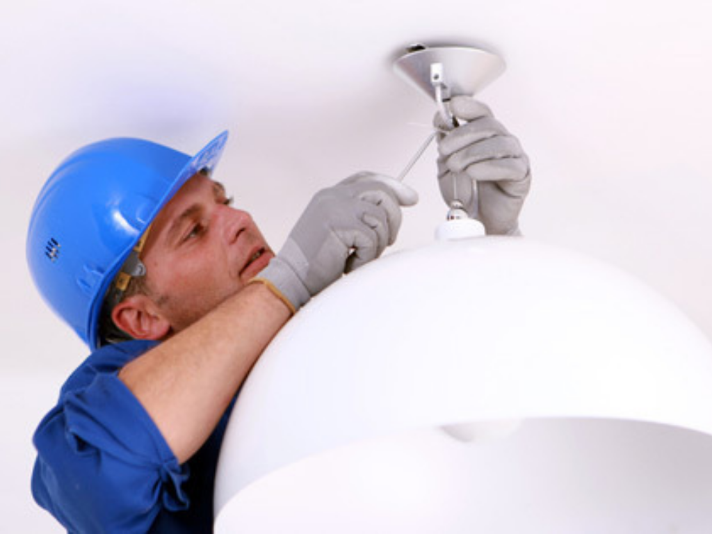 A Man Fixing Light In A Room With A White Background